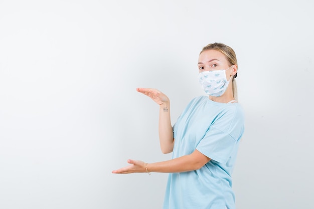 Junge Dame im T-Shirt, Maske mit Größenschild und selbstbewusstem Blick