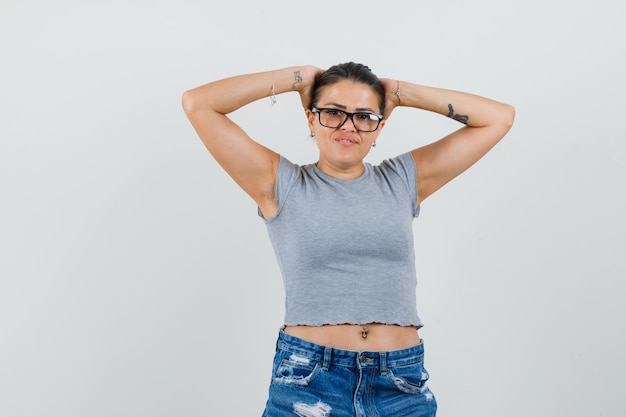 Junge Dame im T-Shirt, Shorts, die Kopf mit den Händen umklammern und selbstbewusst aussehen