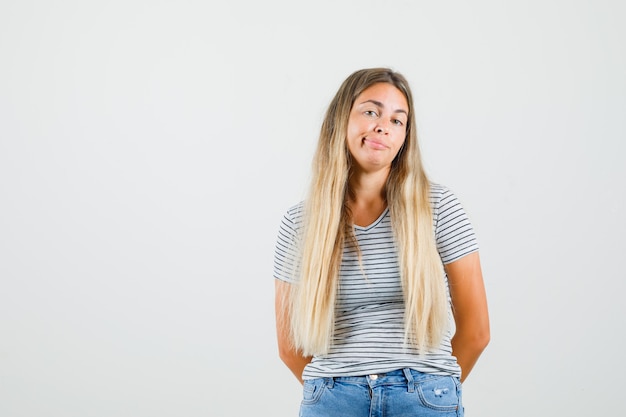 Junge Dame im T-Shirt stehend und faul schauend, Vorderansicht.