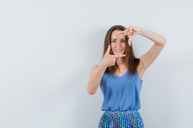 Junge Dame im Unterhemd, Rock, der Rahmengeste macht und lustig schaut