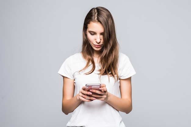 Junge Dame im weißen T-Shirt und in den blauen Jeans bleiben mit Telefon vor weißem Studiohintergrund