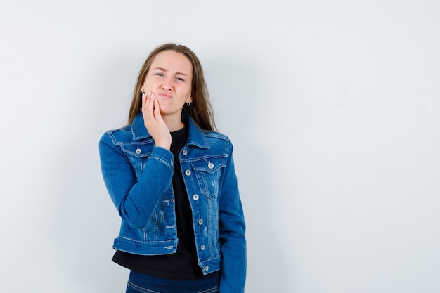 Junge Dame in Bluse, die unter Zahnschmerzen leidet und unbequem aussieht, Vorderansicht.