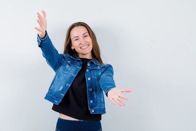 Junge Dame in Bluse, Jacke, die Arme zum Umarmen öffnet und fröhlich aussieht, Vorderansicht.