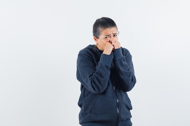 Junge Dame in der Jacke, die Fäuste auf ihrem Mund hält und ängstlich aussieht