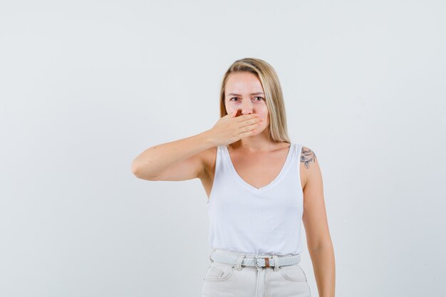 Junge Dame in der weißen Bluse, die Hand auf ihrem Mund hält und besorgt aussieht