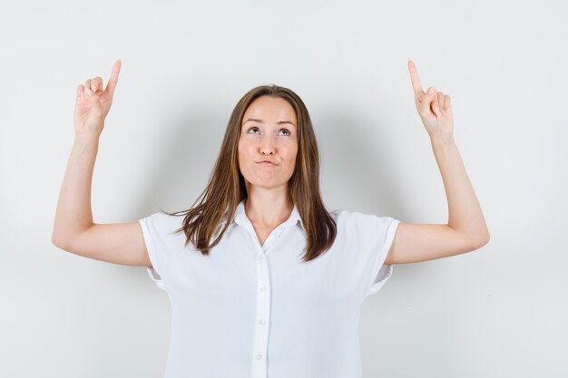 Junge Dame in der weißen Bluse, die oben zeigt und seltsam aussieht