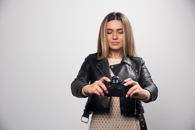 Junge Dame in schwarzer Lederjacke, die ernsthaft und professionell Fotos mit der Kamera macht.
