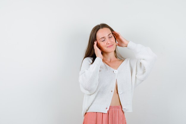 Junge Dame in Strickjacke und Rock, die Schläfen reiben, die niedlich lokalisiert aussehen