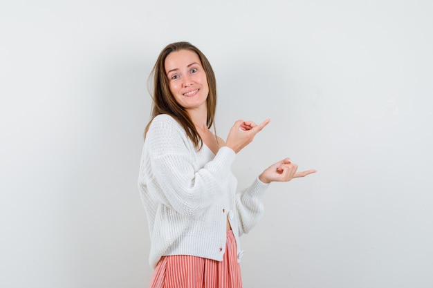 Junge Dame in Strickjacke und Rock zeigt auf die rechte Seite und sieht freudig isoliert aus