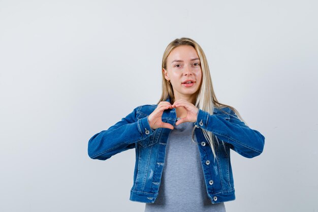 Junge Dame in T-Shirt, Jeansjacke, Rock mit Herzgeste und hübschem Aussehen