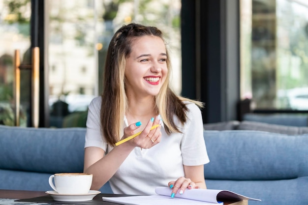 Junge Dame lacht und hält Stift im Restaurant