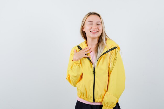 Junge Dame lächelt, während sie im T-Shirt, in der Jacke aufwirft und herrlich schaut