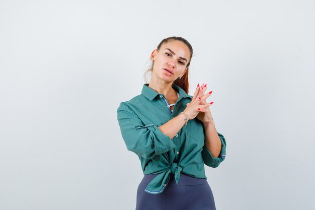 Junge Dame mit Fingern im grünen Hemd umklammert und nachdenklich, Vorderansicht.