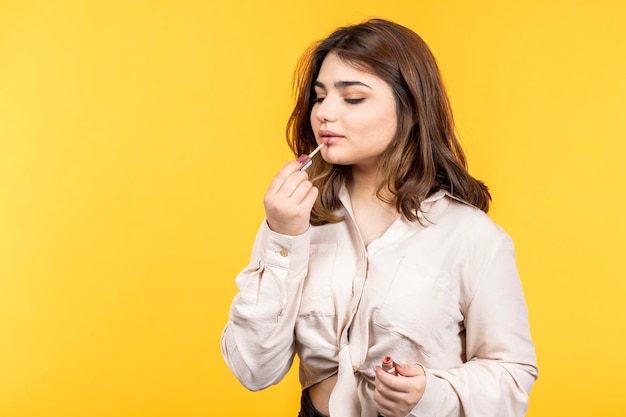 Junge Dame mit Lippenstift auf gelbem Hintergrund Hochwertiges Foto