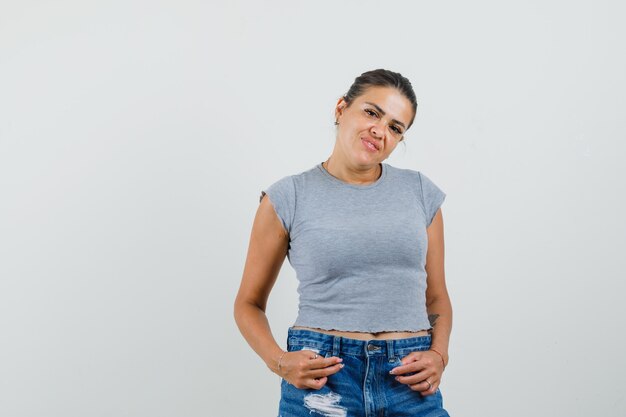 Junge Dame posiert beim Stehen im T-Shirt, in den Shorts und im attraktiven Aussehen.