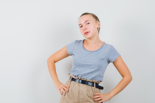 Junge Dame posiert beim Stehen in T-Shirts und Hosen und sieht schön aus