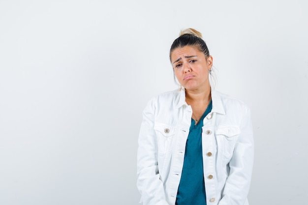 Junge Dame posiert im Hemd, in der weißen Jacke und sieht enttäuscht aus, Vorderansicht.