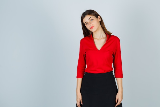 Junge Dame posiert in roter Bluse, schwarzem Rock und sieht hübsch aus