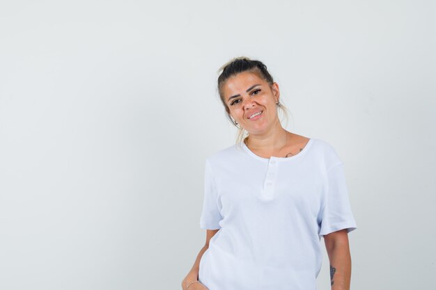 Junge Dame posiert, während sie im T-Shirt steht und glamourös aussieht