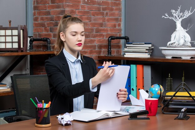 Junge Dame sitzt an einem Tisch und liest ihre Notizen im Notizbuch im Büro