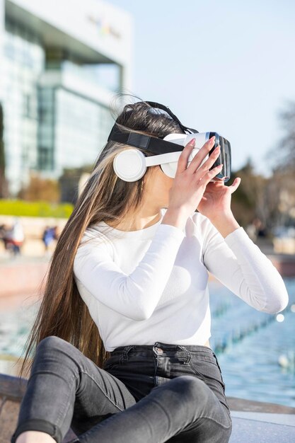 Junge Dame trägt Vr-Set und sitzt im Park Foto in hoher Qualität