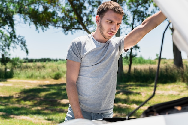 Junge, der aufgeschlüsseltes Auto betrachtet