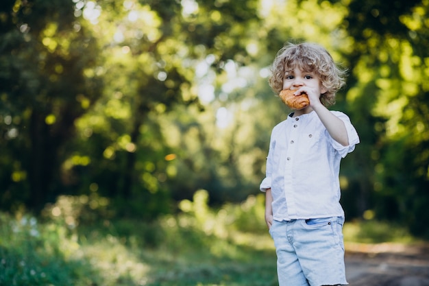 Junge, der croissant im park isst