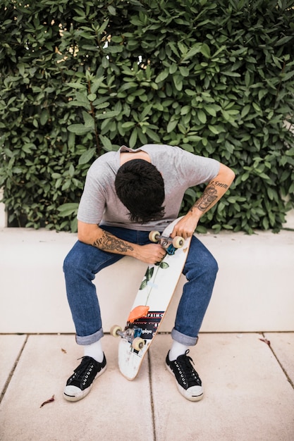 Kostenloses Foto junge, der die räder des skateboards justiert