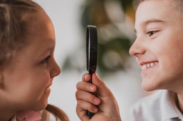 Junge, der ein Mädchen mit einer Lupennahaufnahme betrachtet