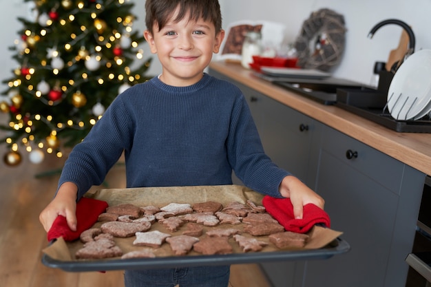 Junge, der ein Tablett voll hausgemachter Lebkuchenplätzchen hält