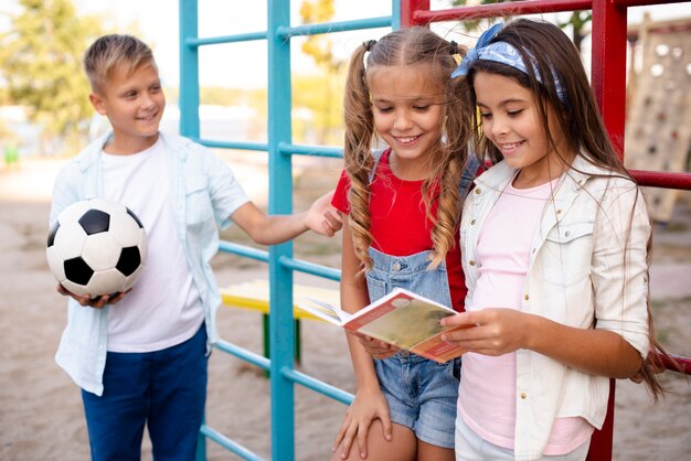 Junge, der einen Ball hält, während Mädchen ein Buch lasen