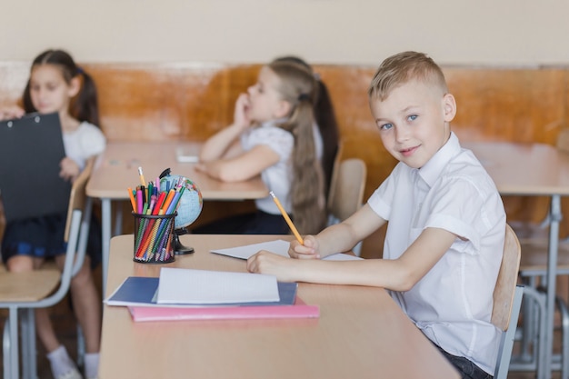 Junge, der im klassenzimmer und im schreiben sitzt