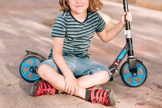 Junge, der im Park mit Roller sitzt