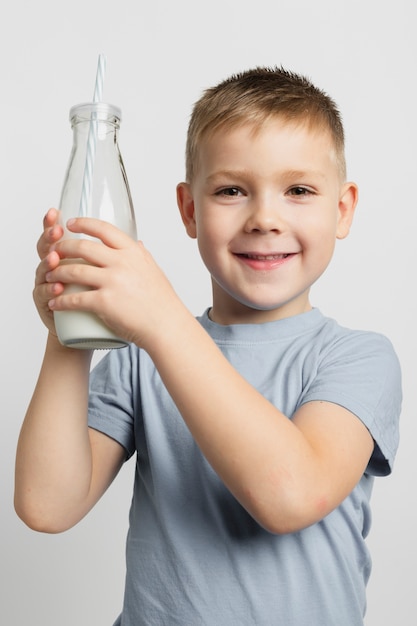 Junge, der Milchflasche mit Stroh hält