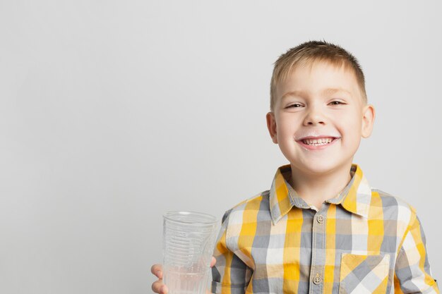 Junge, der Milchglas lächelt und hält