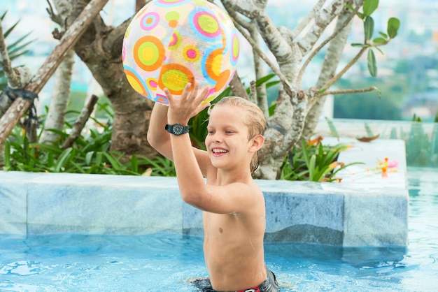 Junge, der mit Ball im Pool spielt