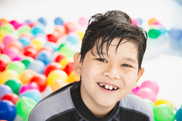 Junge, der mit buntem Ball im kleinen Swimmingpoolspielzeug spielt