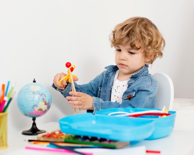 Junge, der mit Spielzeug am Schreibtisch spielt