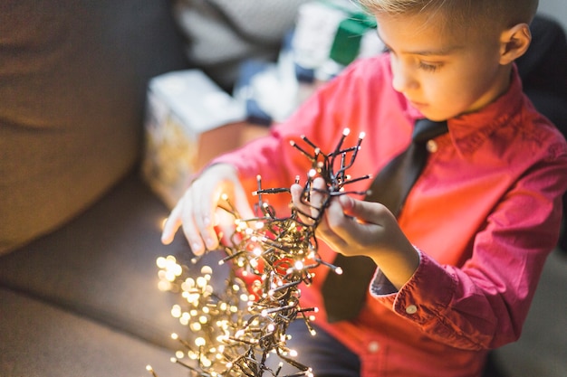 Junge, der mit Weihnachtslichtern spielt