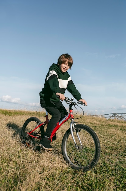 Junge, der sein Fahrrad auf Gras draußen reitet