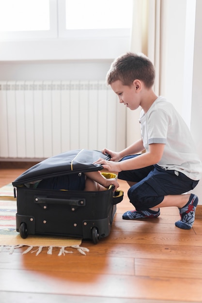 Junge, der seinen Bruder im Gepäck verpackt