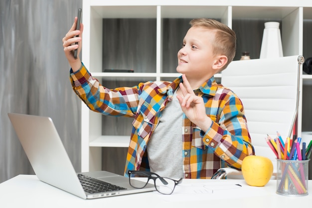 Junge, der selfie am Schreibtisch nimmt