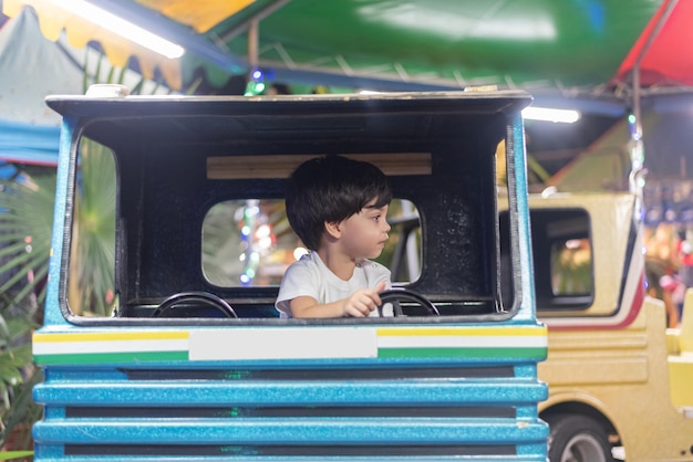 Junge, der Spielzeuglastwagen im Vergnügungspark fährt