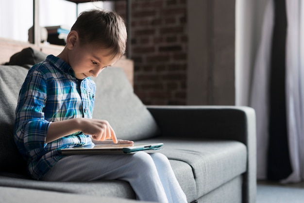 Kostenloses Foto junge, der tablette auf couch verwendet