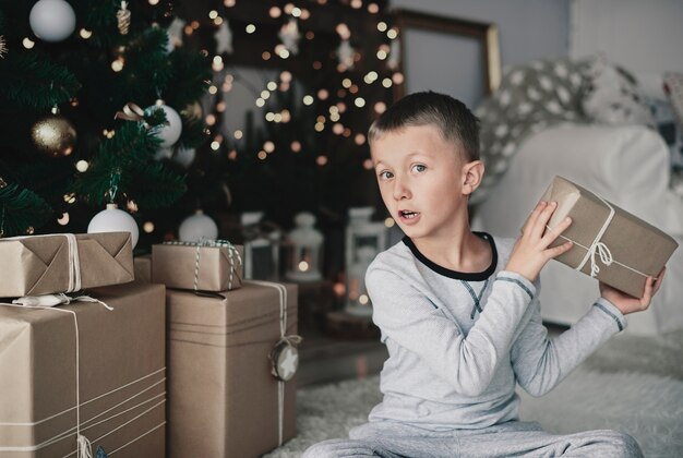 Junge, der Weihnachtsgeschenke neben Weihnachtsbaum arrangiert