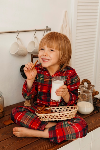 Junge, der Weihnachtsplätzchen isst und Milch trinkt