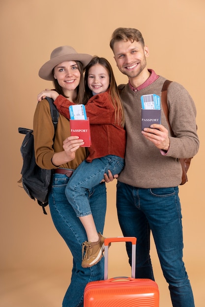 Junge dreiköpfige Familie, die vor Reiseferien zusammen posiert