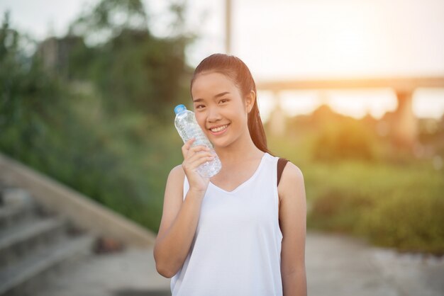 Junge Eignungsfrauenhand, die Wasserflasche hält, nachdem Übung laufen gelassen worden ist