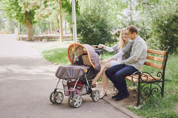Junge Eltern mit Kinderwagen im Park lachen