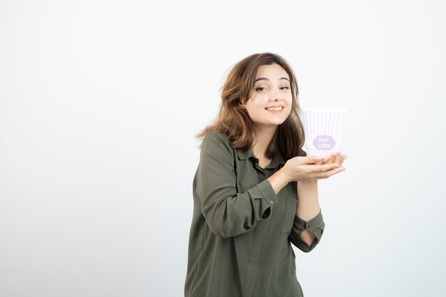 Junge entzückende Frau, die Popcorn-Box hält und posiert. Foto in hoher Qualität